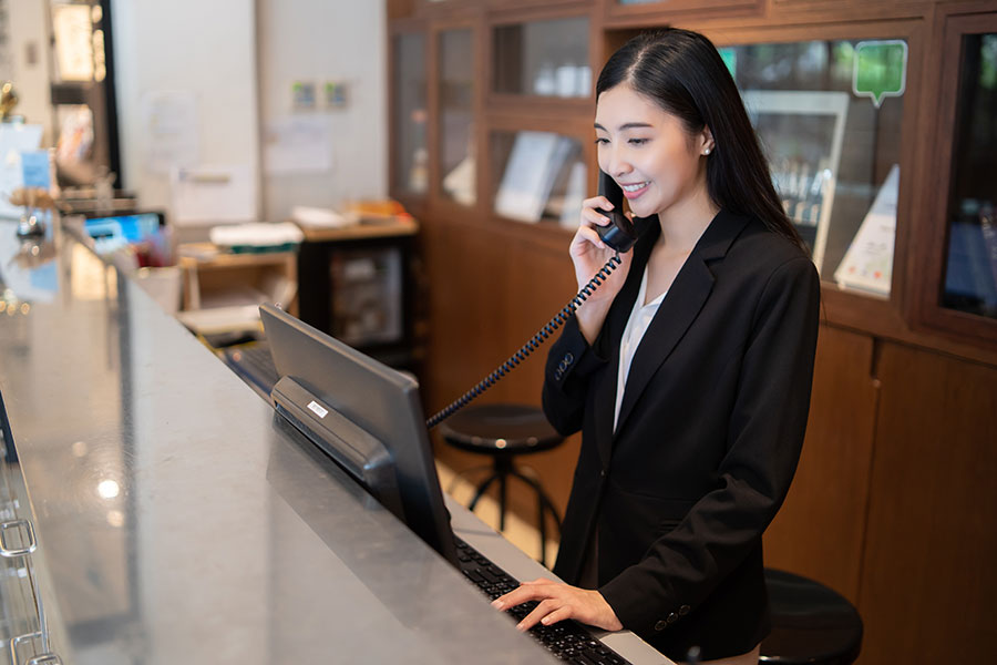 Business Insurance - Hotel Receptionist Takes a Call at the Large Welcoming Desk